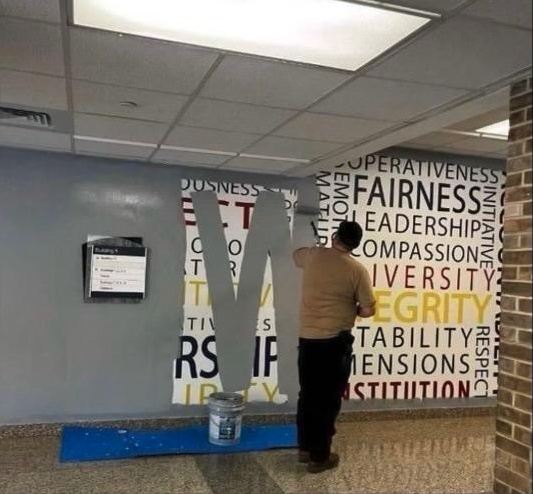 Gray paint is applied to a wall at the FBI Training Academy (Quantico), painting over the words "Fairness," "Leadership," "Diversity," and "Integrity."