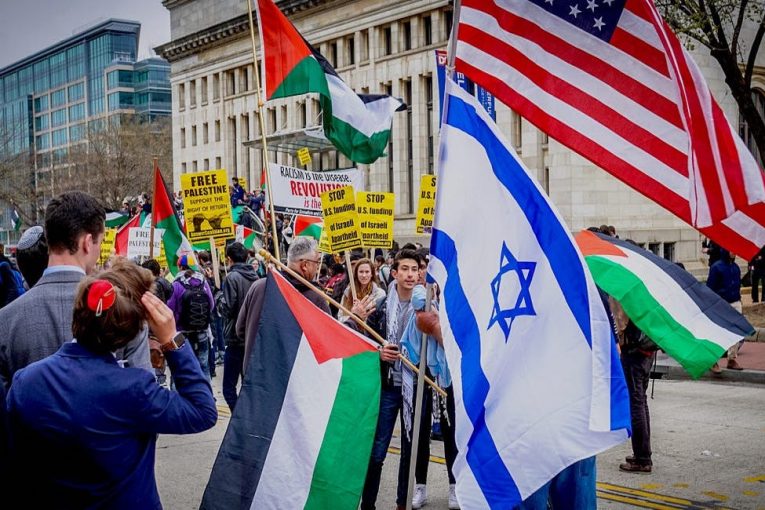 Protestors wave Palestinian, Israeli, and American flags.
